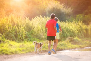 Active seniors running with their dog outside in green nature