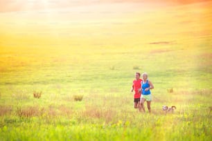 Active seniors running with their dog outside in green nature