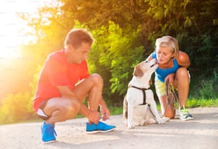 Active seniors getting ready for a run with their dog outside in green nature