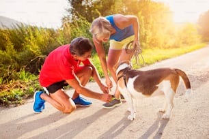 Active seniors getting ready for a run with their dog outside in green nature