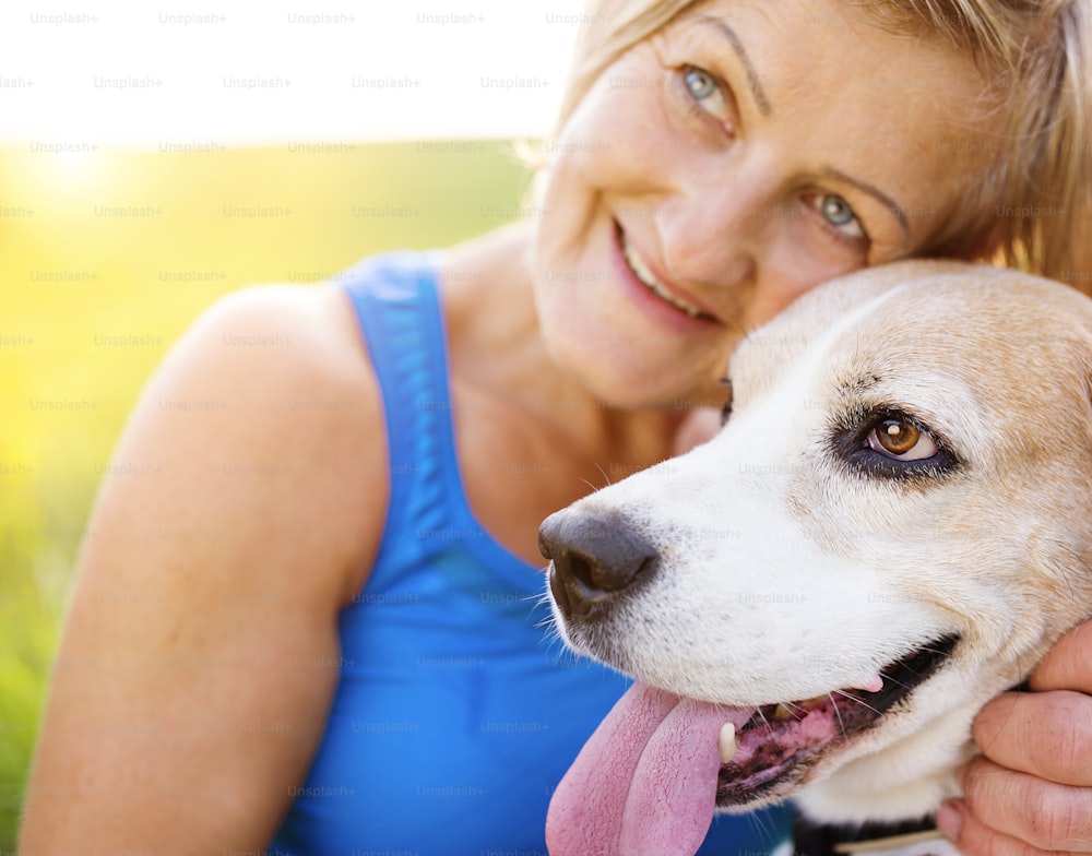Active senior woman with her dog on a run outside in green nature