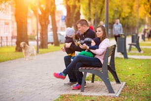 Jeune famille heureuse lors d’une promenade dans le parc de la ville d’automne