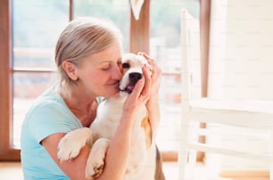 Senior woman with dog inside of her house.