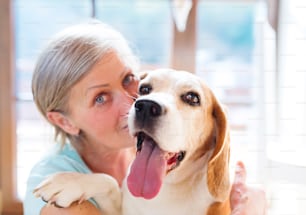 Senior woman with dog inside of her house.