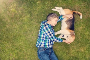 Beautiful senior woman with a dog lying on a grass