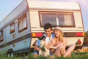 Beautiful young couple in front of a camper van on a summer day