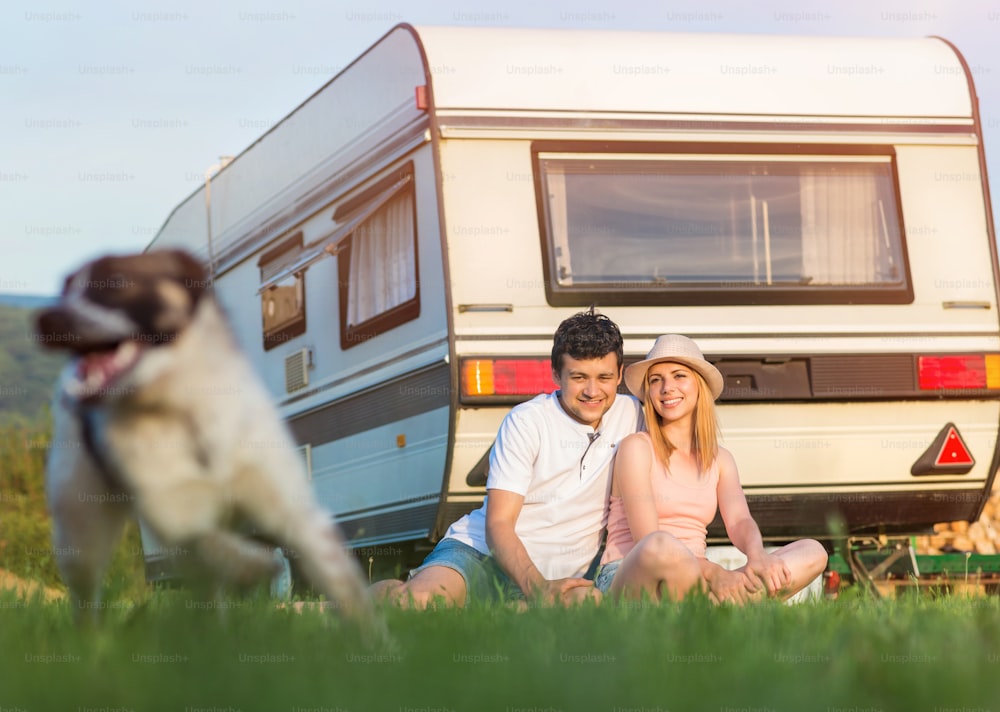 Beautiful young couple in front of a camper van on a summer day