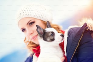 犬の子犬と雪の中で楽しむ魅力的な若い女性