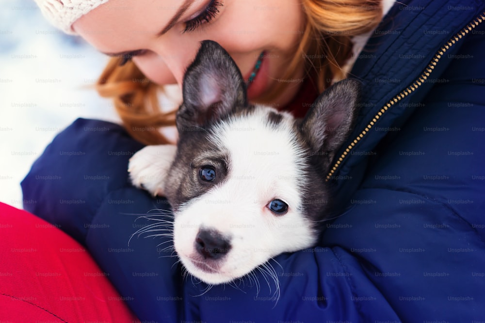 Atractiva joven divirtiéndose afuera en la nieve con su cachorro de perro