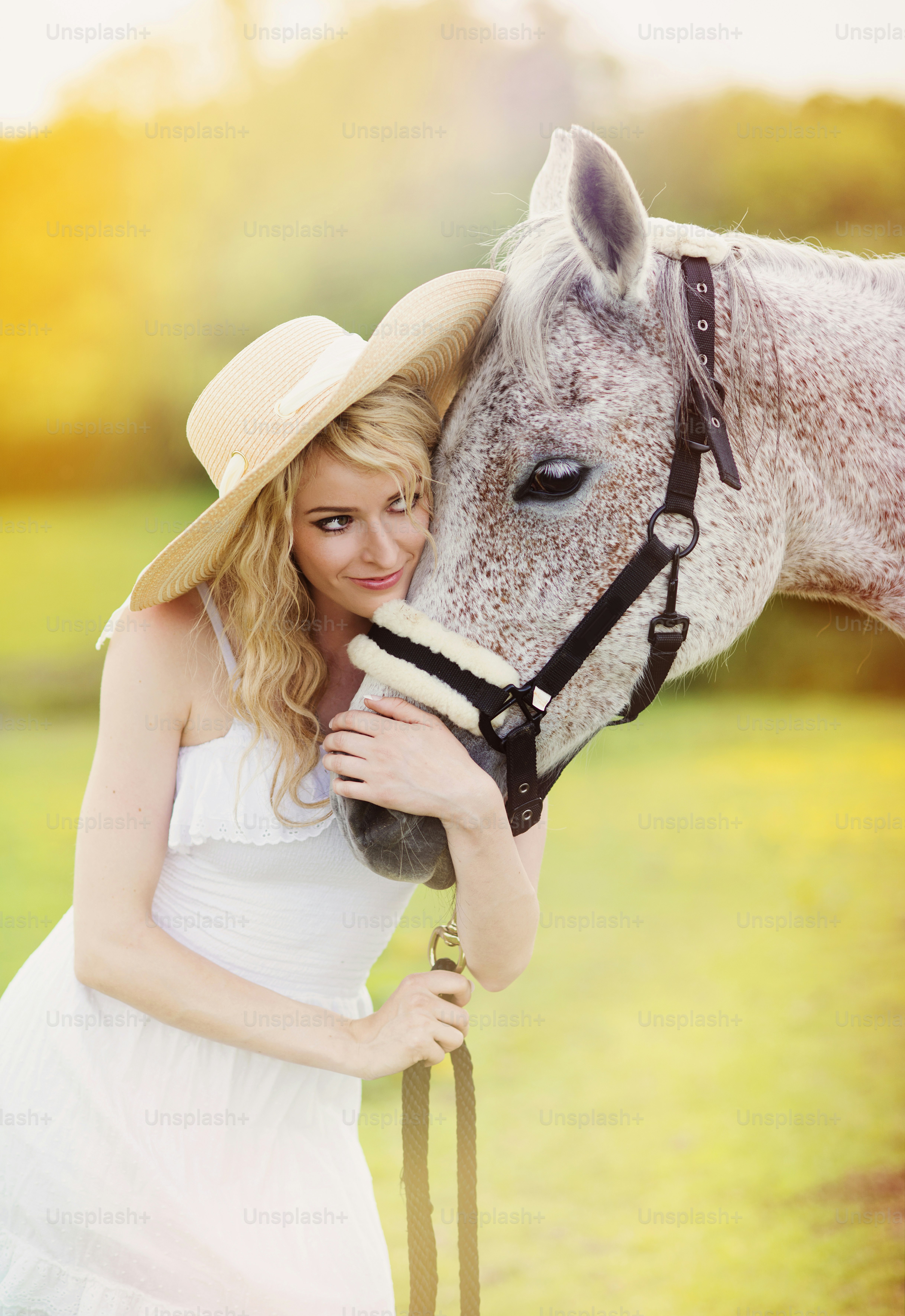 Femme en robe blanche marchant à cheval dans une campagne verdoyante ...