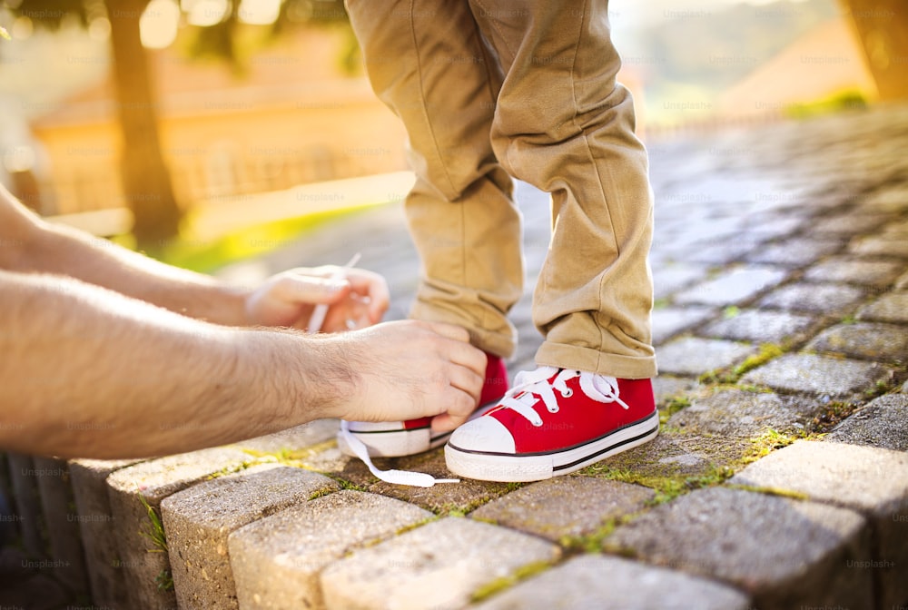 어린 아들의 신발을 ��묶는 아버지의 손의 세부 사항