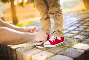 幼い息子の靴を結ぶ父親の手の詳細