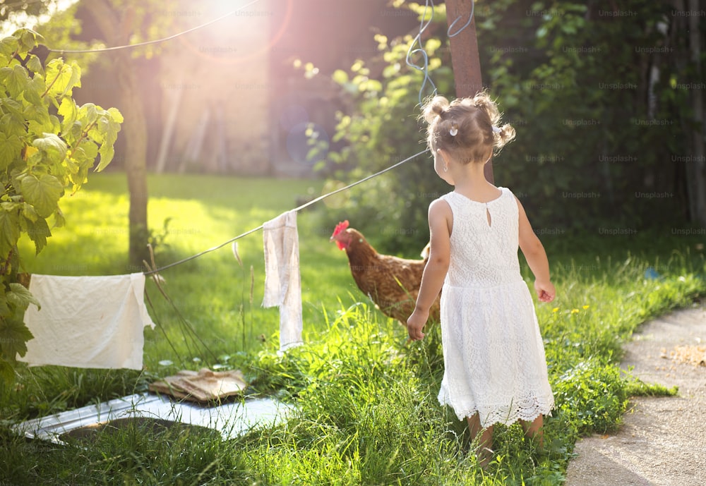 Happy little girl having fun in garden near the old farmhouse