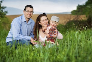 Familia feliz jugando con su hijo en el prado
