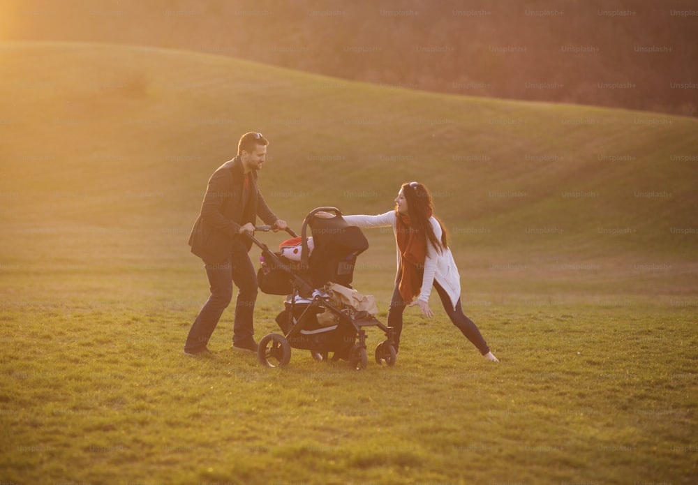 Famiglia felice e giovane con carrozzina durante la passeggiata nella natura