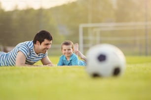 Giovane padre con il suo piccolo figlio che si diverte sul campo di calcio
