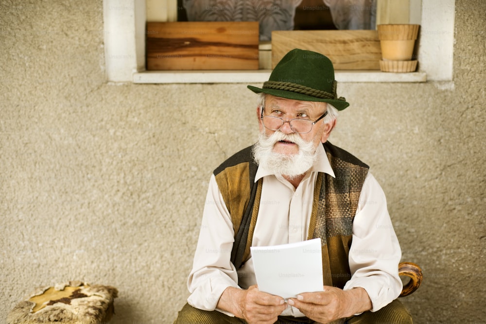 Alter Mann, der die Zeitung vor seinem Haus liest