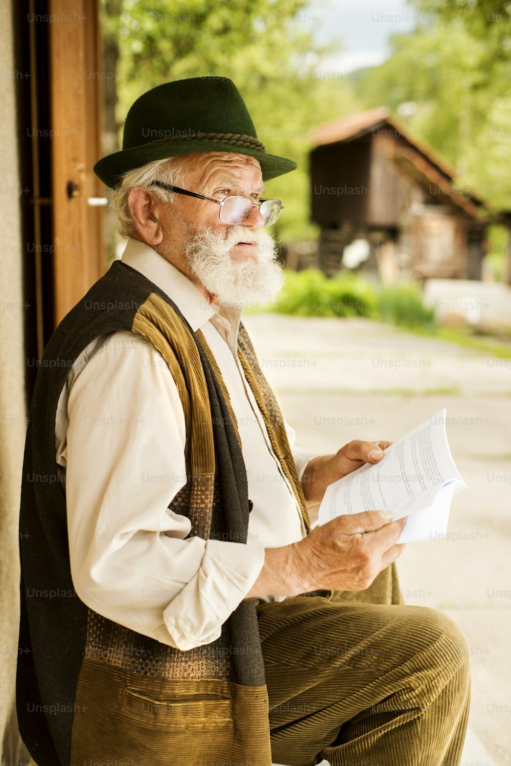 Anciano leyendo el periódico frente a su casa