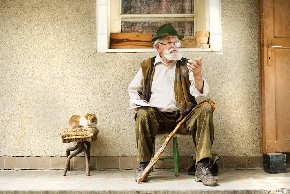 Alter Mann, der die Zeitung vor seinem Haus liest