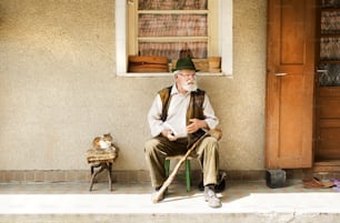 Old man reading the newspaper in front of his house