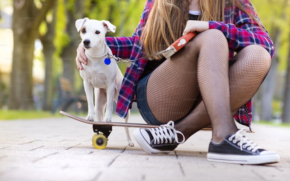 강아지와 함께 스케이트보드를 타는 십대 소녀의 다리 클로즈업
