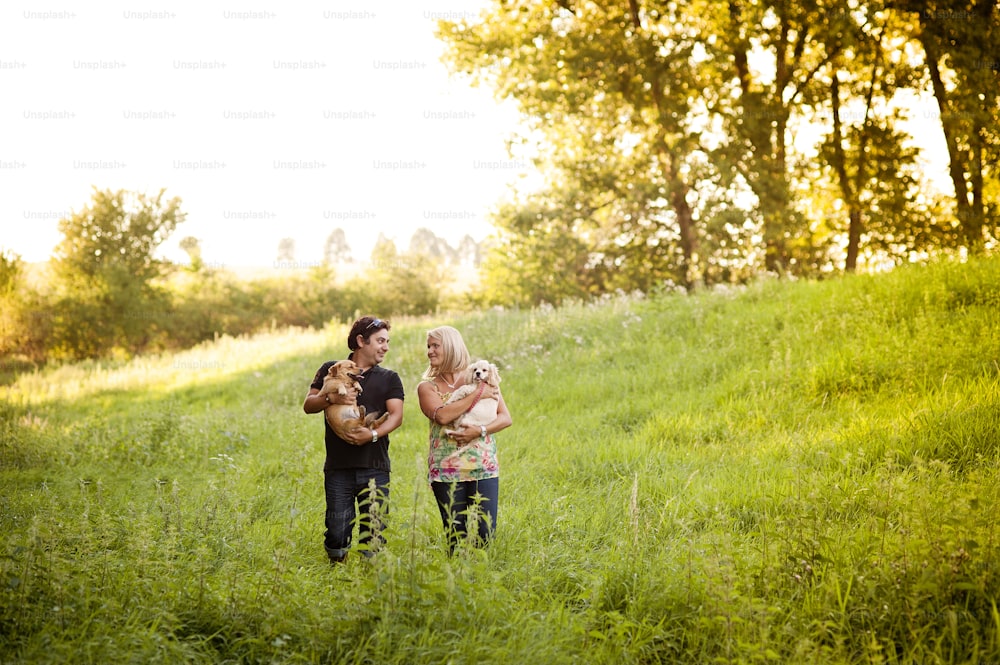 Happy young couple is walking their two dogs in green nature