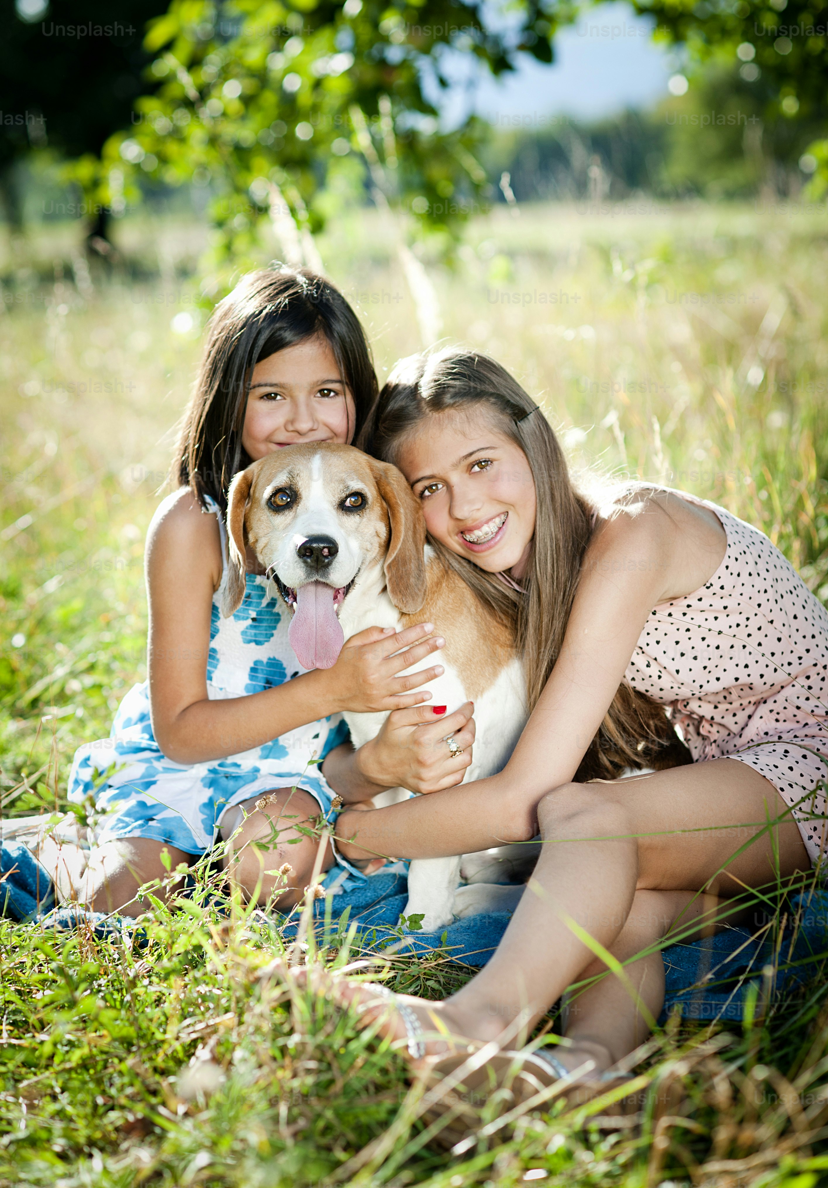 Foto Dos hermanas jugando con su perro beagle en un parque verde y ...