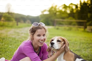 Mulher jovem feliz com seu cão beagle no parque verde