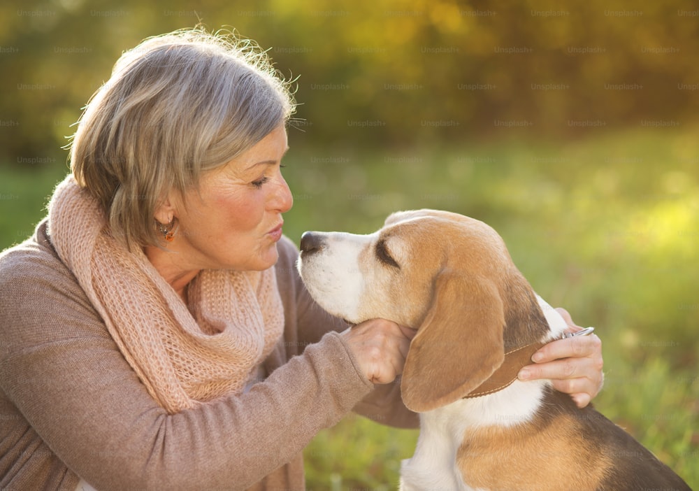 Mujer mayor abraza a su perro beagle en el campo