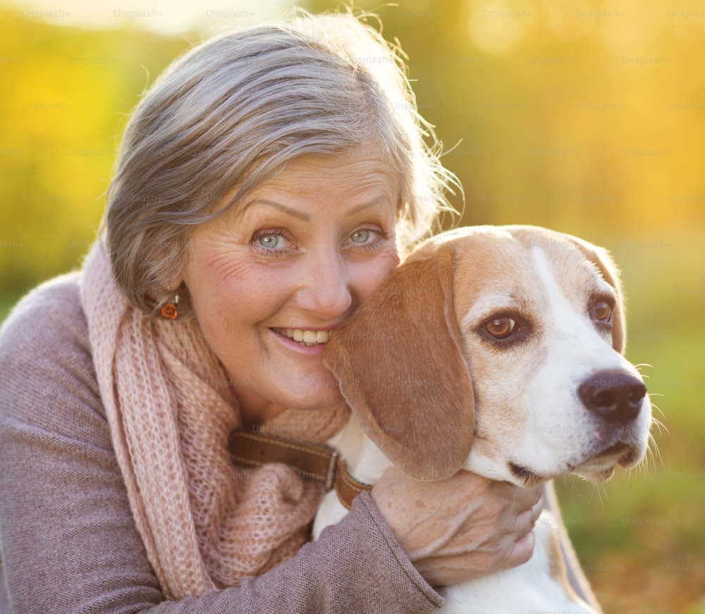 Mujer mayor abraza a su perro beagle en el campo