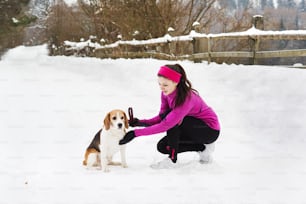 Athlete woman is running during winter training outside in cold snow weather.