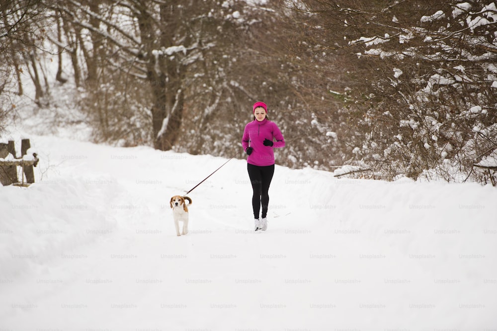 운동선수 여자는 추운 눈 날씨에 밖에서 겨울 훈련 중에 달리고 있다.