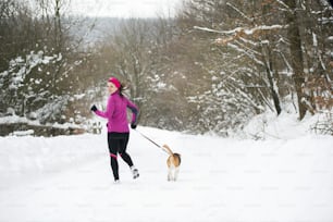 Athlete woman is running during winter training outside in cold snow weather.