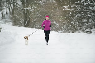 Athlete woman is running during winter training outside in cold snow weather.