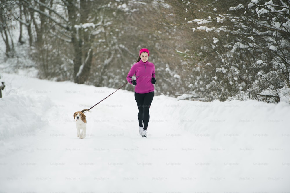 アスリートの女性は、寒い雪の天候の中で屋外で冬のトレーニング中に走っています。