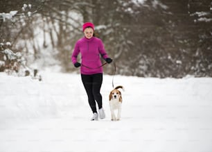 운동선수 여자��는 추운 눈 날씨에 밖에서 겨울 훈련 중에 달리고 있다.