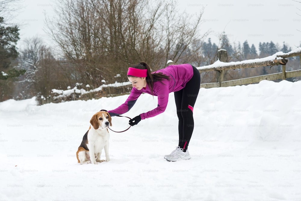 La mujer atleta está corriendo durante el entrenamiento de invierno afuera en clima de nieve fría.