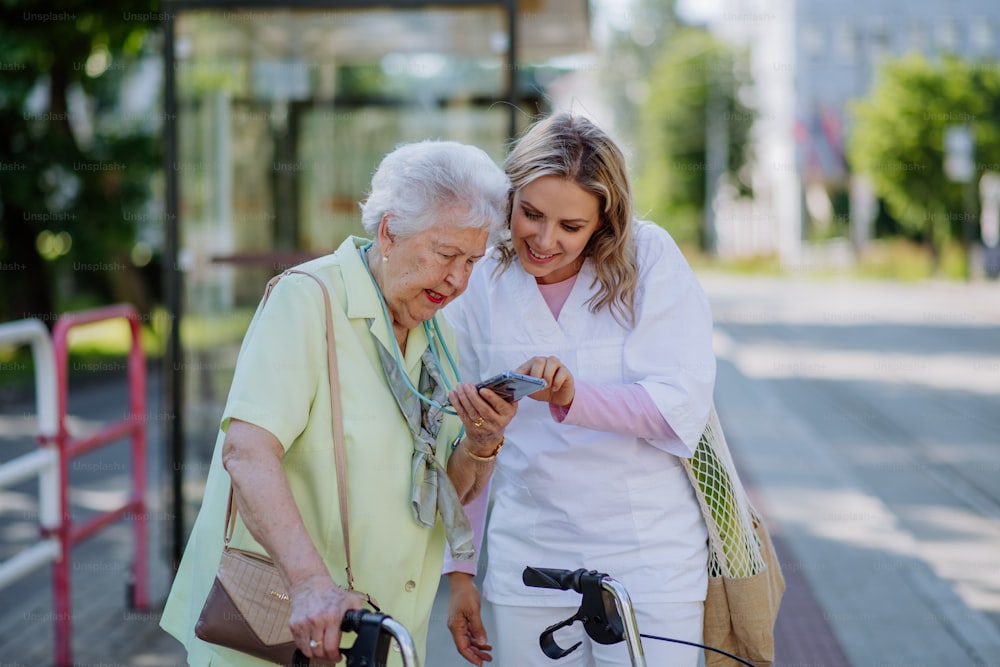 A portrait of caregiver with senior woman on walk in park with shopping bag, laughing and talking.