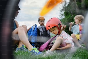 Eine junge Familie mit kleinen Kindern, die sich nach einer Radtour ausruht und im Sommer auf Gras im Park sitzt.
