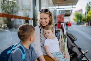 도시의 버스 정류장에서 기다리는 어린 아이들을 둔 젊은 어머니.