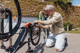 A happy father with teenage daughter repairing bicycle in street.A happy father with teenage daughter repairing bicycle in street, high angle view.