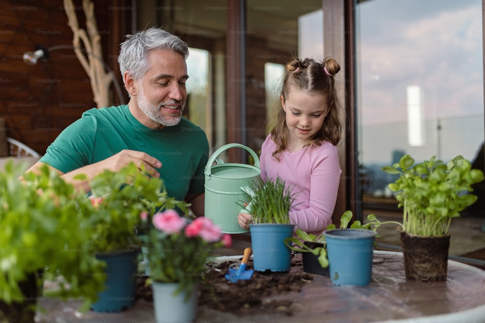 A little daughter helping father to plant and water flowers, home gardening concept