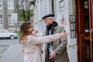 Eine erwachsene Tochter begrüßt ihren älteren Vater, als sie ihn draußen auf der Straße trifft.