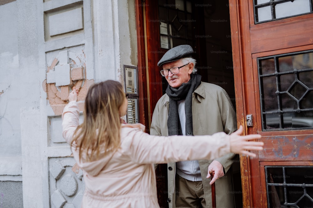 An adult daughter greeting her senior father when meeting him outdoors in street.