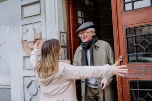Une fille adulte saluant son père aîné lorsqu’elle le rencontre à l’extérieur dans la rue.