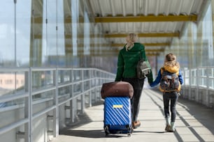 Una vista posteriore della madre immigrata ucraina con il bambino con i bagagli che camminano alla stazione ferroviaria, concetto di guerra ucraina.