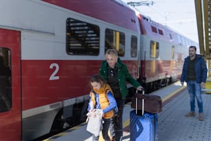 Eine ukrainische Einwandererfamilie mit Gepäck wartet am Bahnhof, ukrainisches Kriegskonzept.