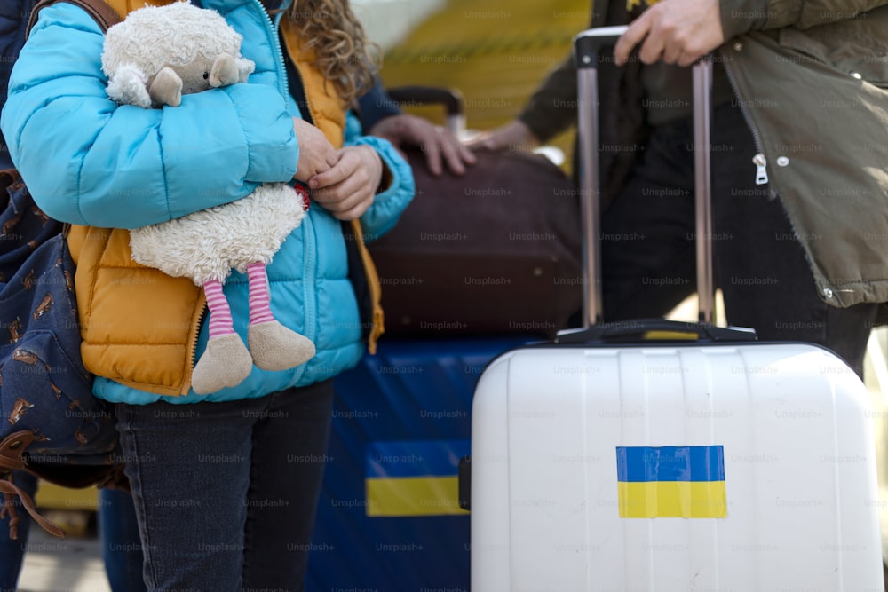 A close-up of Ukrainian immigrants with luggage waiting at train station, Ukrainian war concept.
