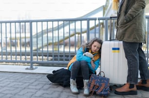 Immigrati ucraini con bagagli in attesa alla stazione ferroviaria, concetto di guerra ucraina.