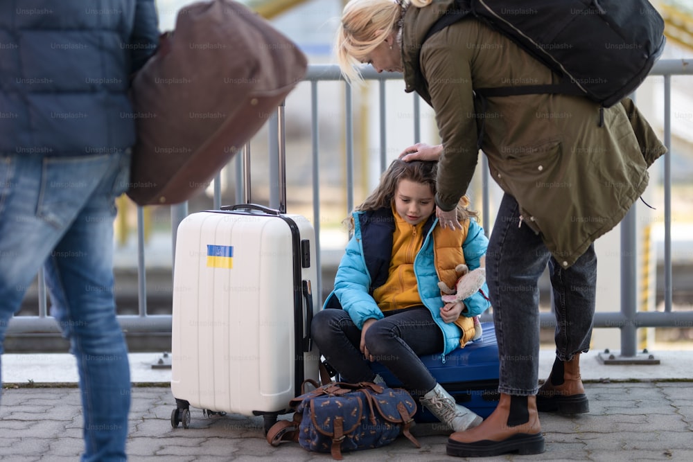 Ukrainian immigrants with luggage waiting at train station, Ukrainian war concept.